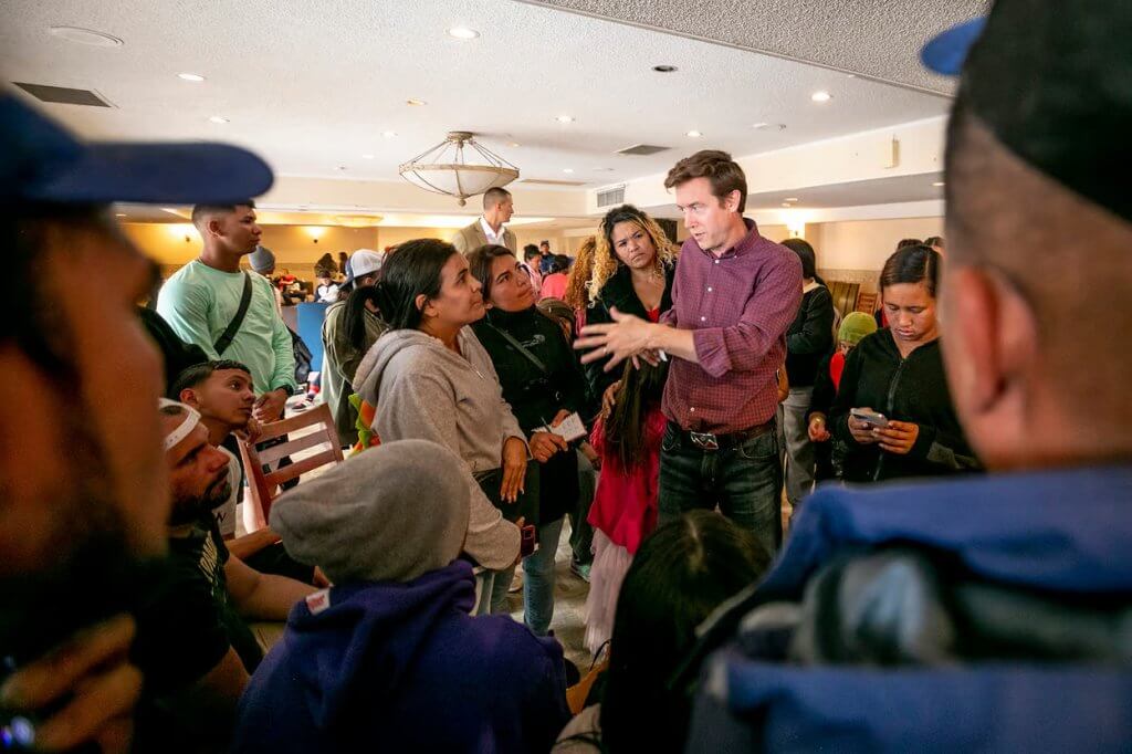 Denver Mayor Mike Johnston speaks with a group of new immigrants. Denverite