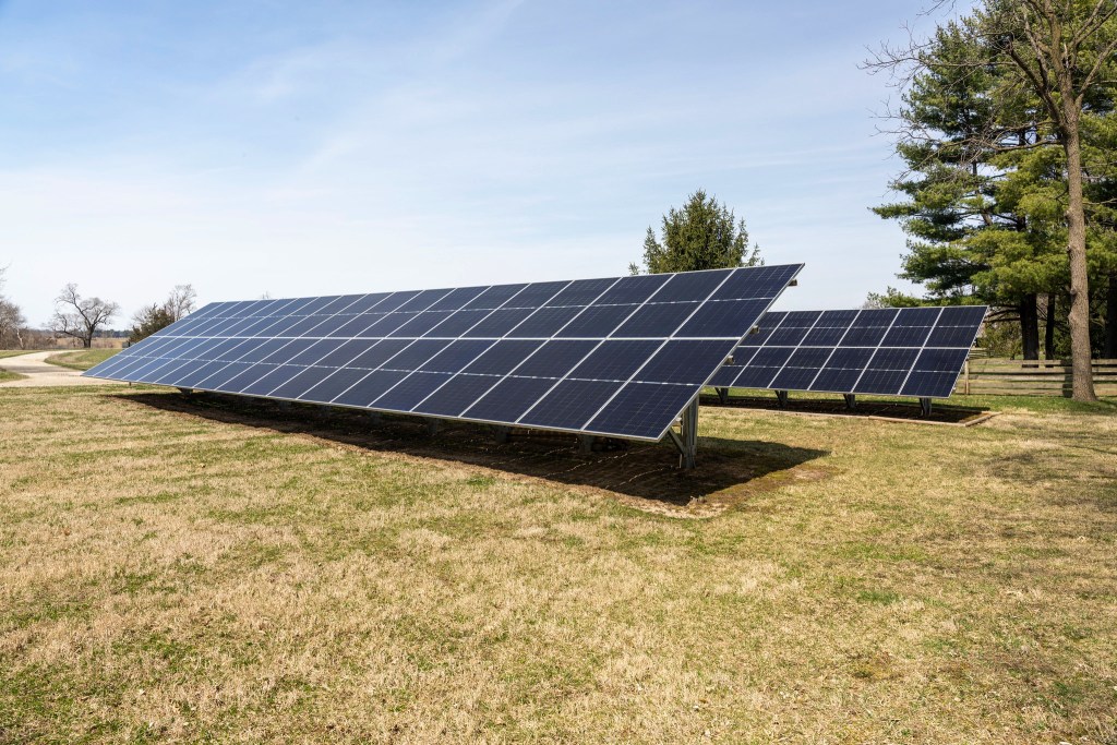 Solar panels in a grassy area near a farm
